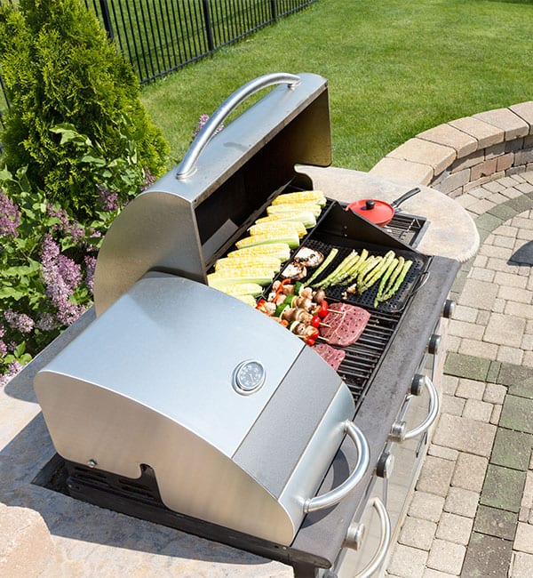 a backyard grass grill loaded with meat and veggies