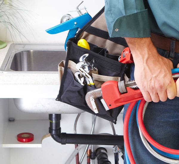 generic photo of plumber in tool belt with red plumbers wrench