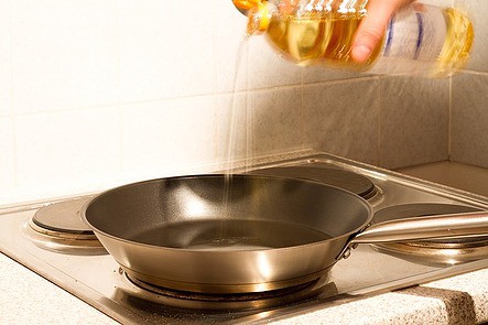a non-stick pan on a stove with olive oil being poured into it