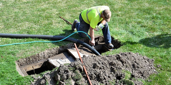 man cleaning out a septic tank on a summer day